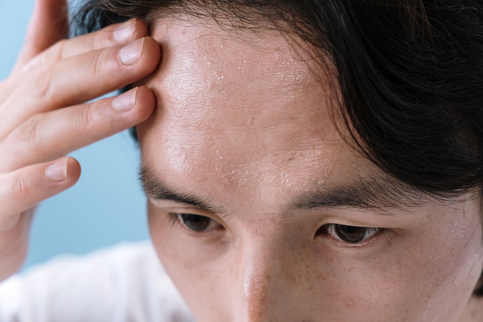 Man wiping sweat from his forehead indoors during a Southern California heat wave when the AC isn't cooling