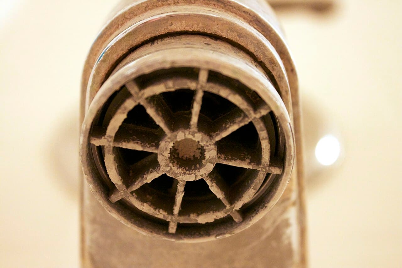 Heavy white calcium and limescale deposits caked on a bathroom faucet aerator from hard water