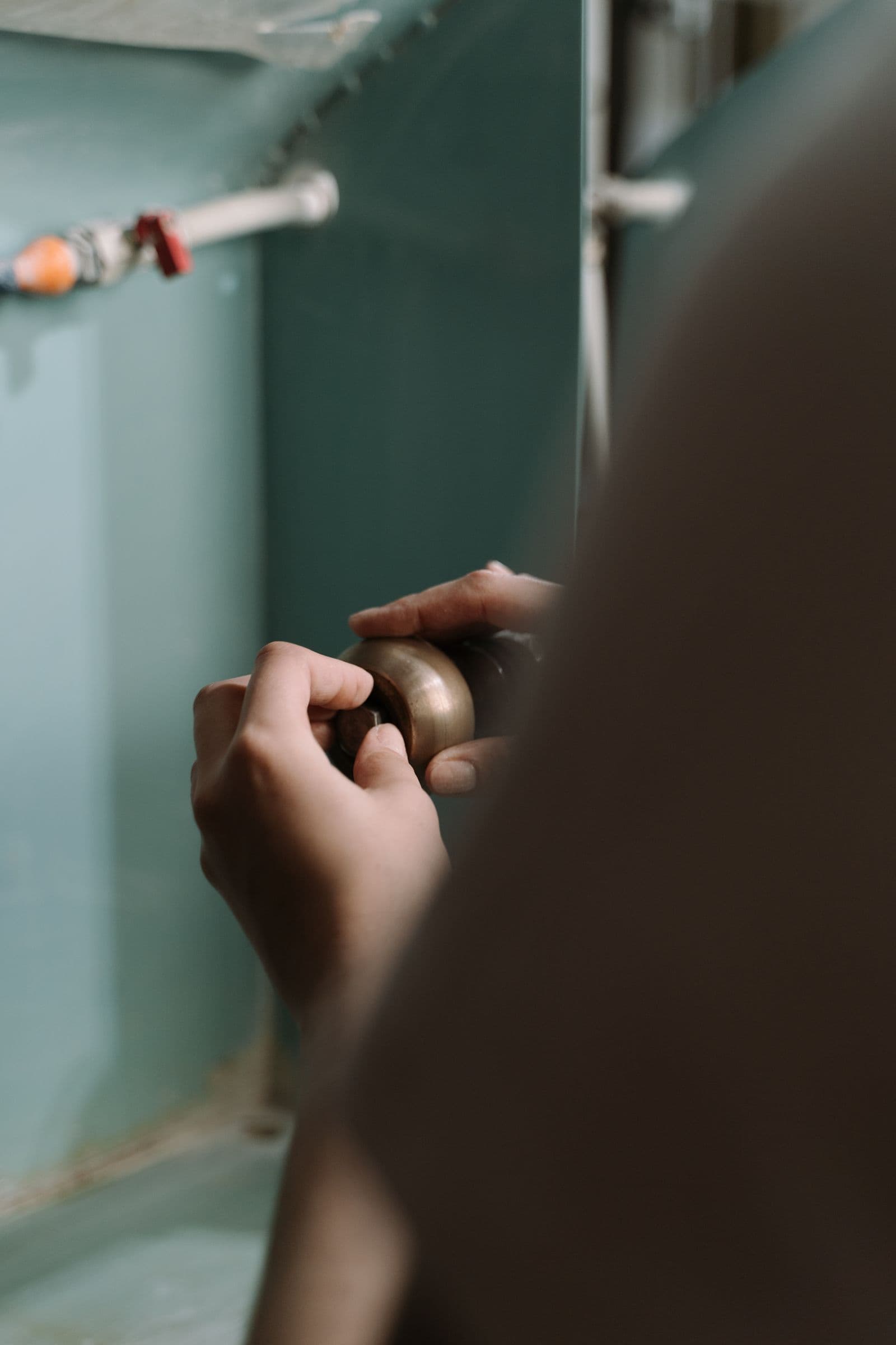 Plumber working on residential water pipes under a kitchen sink during a plumbing upgrade