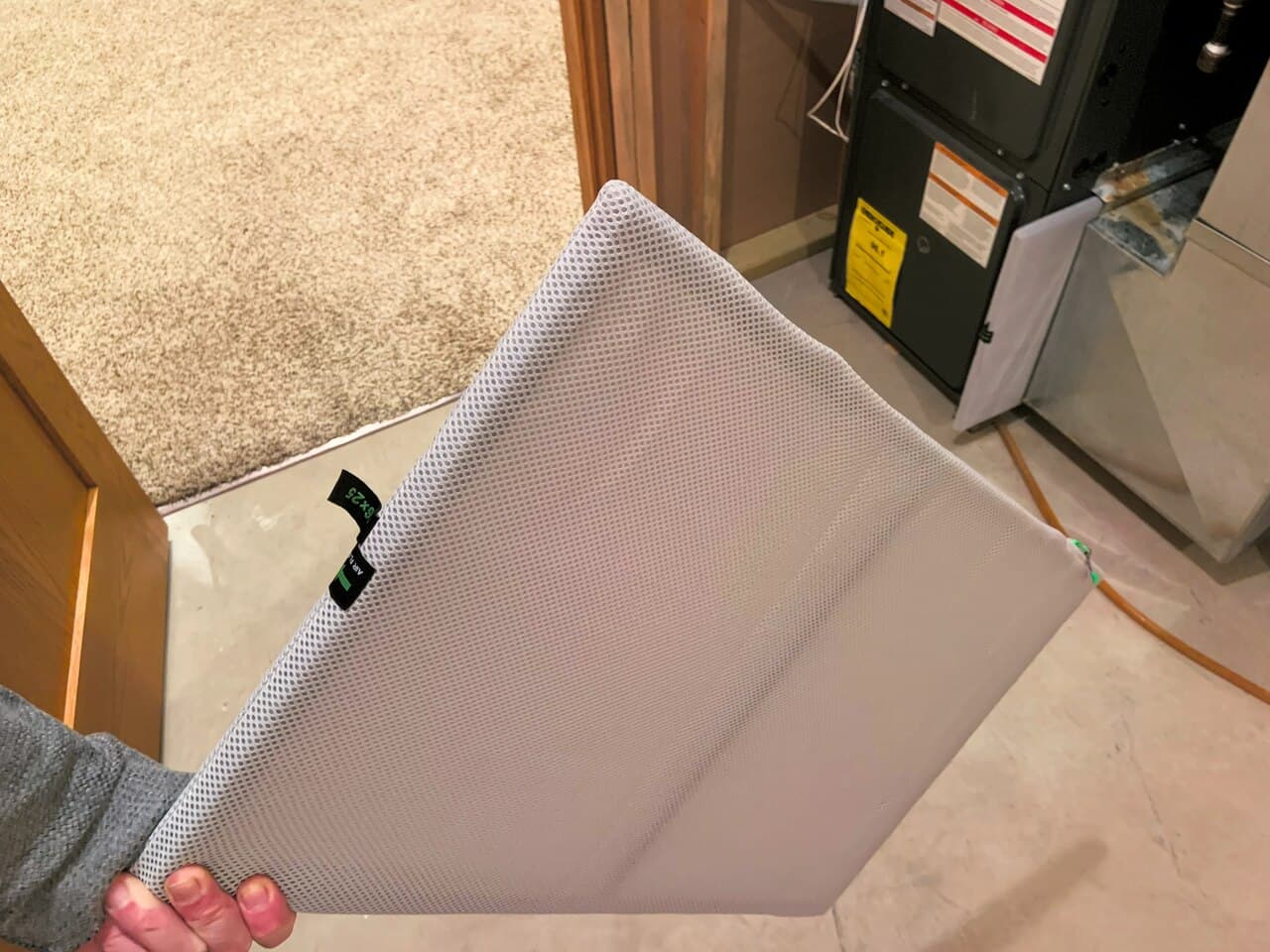 Homeowner holding a residential HVAC air filter in front of a furnace cabinet after a wind event